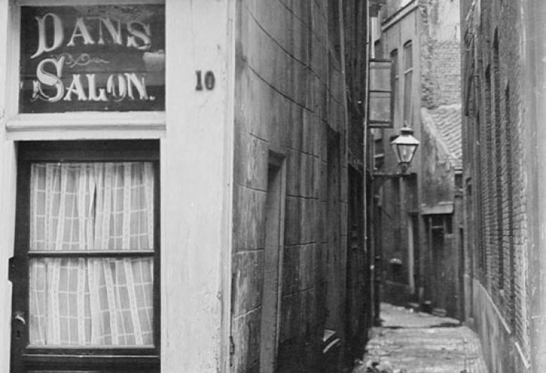 De Mosterdsteeg gezien vanuit de Zandstraat. Op de voorgrond een toegangsdeur tot een danssalon met straatnummer 10.