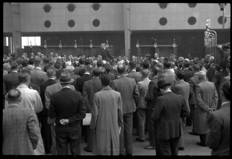 Kamer van Koophandelvoorzitter K.P. van der Mandele maakt in het Beursgebouw aan een groot aantal toehoorders de capitulatie van Japan bekend.