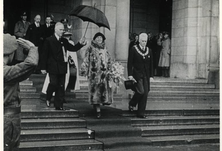 Het eerste bezoek na de bevrijding van koningin Wilhelmina aan Rotterdam. Koningin Wilhelmina verlaat met burgemeester Oud het stadhuis. Collectie 4282, 1975-498. Fotograaf Polygoonjournaal