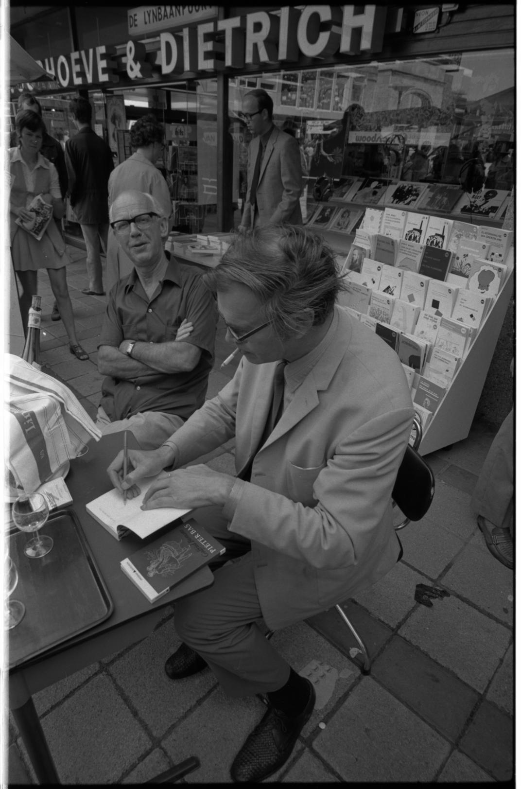Godfried Bomans signeert zijn boek Pieter Bas voor de boekwinkel van Voorhoeve en Dietrich aan de Lijnbaan, Fotograaf Ary Groeneveld