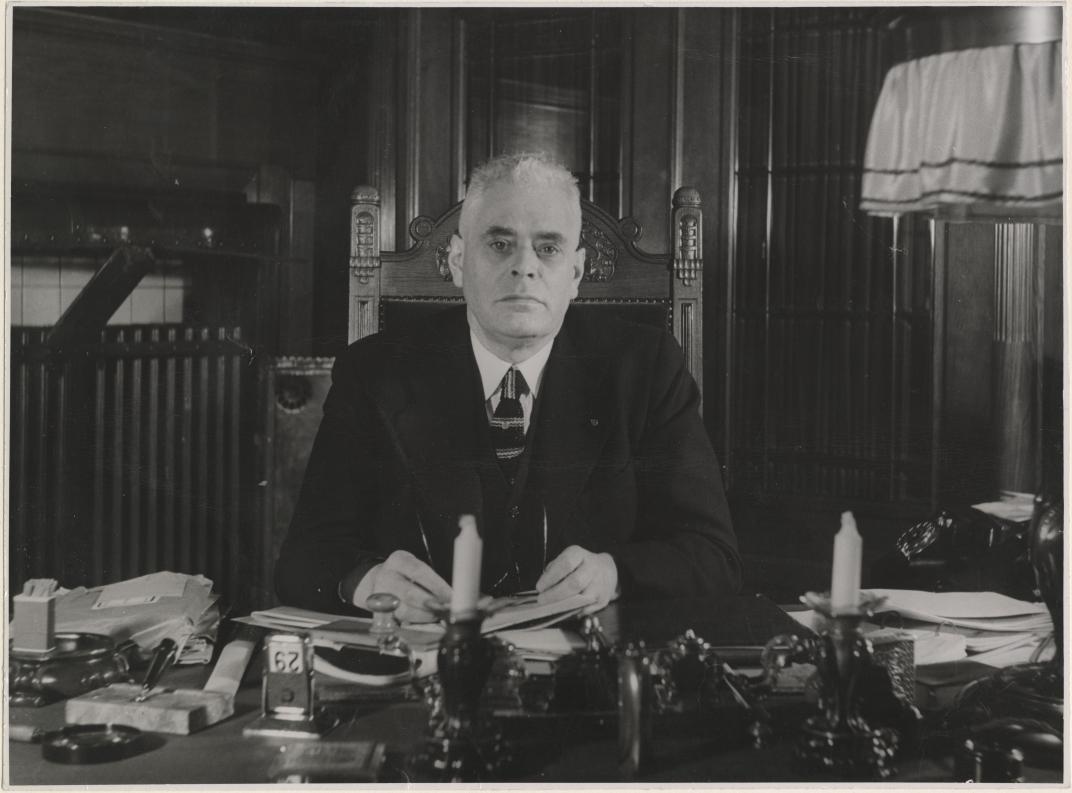 Portret van mr. Pieter Jacobus Oud werkend aan zijn bureau in zijn kamer van het stadhuis aan de Coolsingel. Fotograaf: Erich Hof