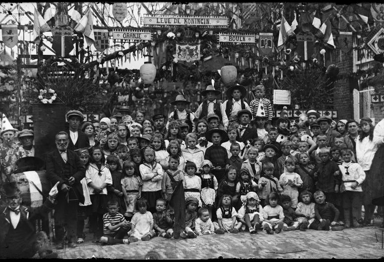 Op Koninginnedag 1923 poseert een grote groep kinderen in een versierde Isaäc Hubertstraat. Sommige kinderen zijn verkleed. Collectie Lex de Herder, nummer 4126, R4931