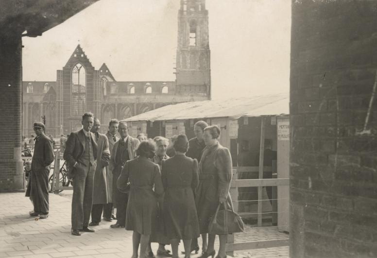 Een groepje mensen staat onder het spoorviaduct. 