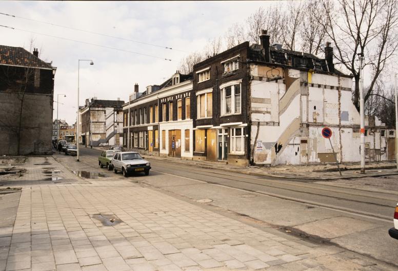 In de Crooswijksestraat worden huizen gesloopt. De ramen en deuren van de panden in de straat zijn dichtgetimmerd. De foto is vanaf de hoek bij de 2e Crooswijksedwarsstraat in westelijke richting gemaakt. 20 maart 1988.