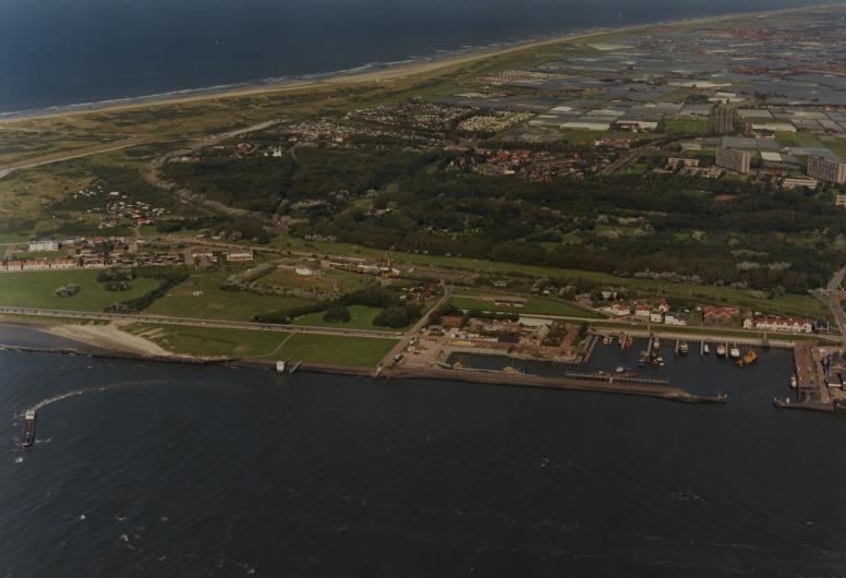 Luchtopname van Hoek van Holland uit het zuiden gezien. Op de voorgrond de Nieuwe Waterweg met rechts de Berghaven, in het midden de duinen en op de achtergrond links het strand en de Noordzee en rechts het kassengebied van het Westland, 14-09-1987. Colle