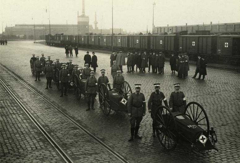 Een groep frontverpleegkundigen van het Rode Kruis op transport in de Schiehaven in verband met de mobilisatie in afwachting van de Eerste Wereldoorlog. Rechts de Westzeedijk met de goederenloods van de spoorwegen. Collectie 4282 XXXIII-295-4