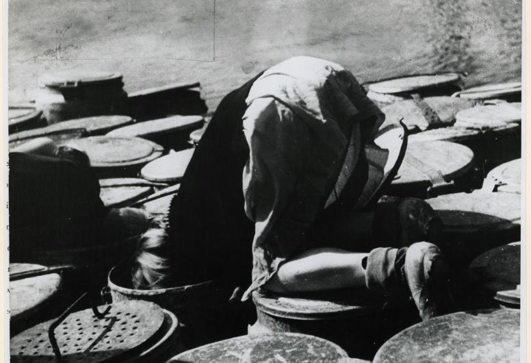 Gedwongen door de schaarste zoekt een kind naar voedselresten in vuilnisbakken tijdens de Hongerwinter. 