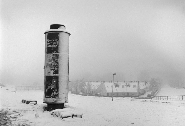 Schiedamseweg met reclamezuil nabij het Marconiplein. Sneeuw tussen kerst en nieuwjaar. Op de achtergrond rechts het Witte dorp. 1985. Collectie 4100 Documentnummer 1986-296