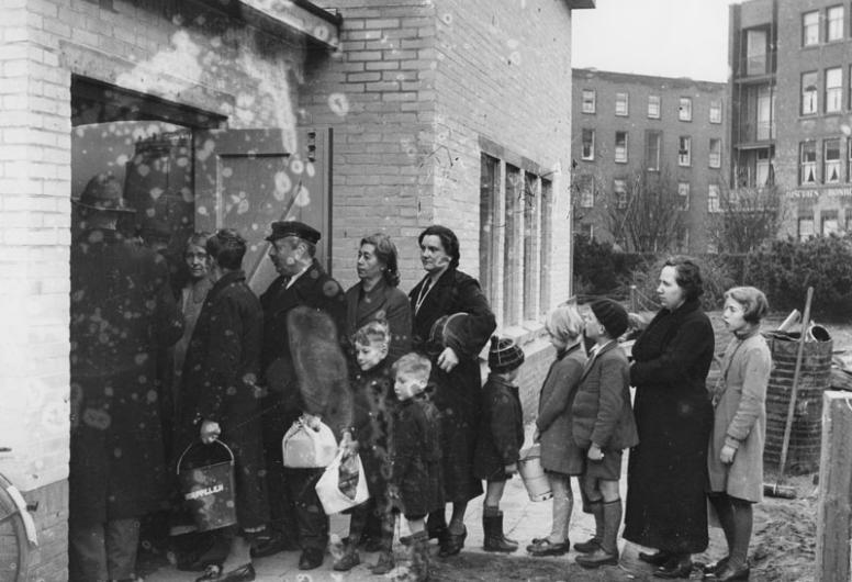Mensen in de rij voor voedseluitdeling van de centrale keuken of gaarkeuken aan het Grote Visserijplein, 1943 - 1945.