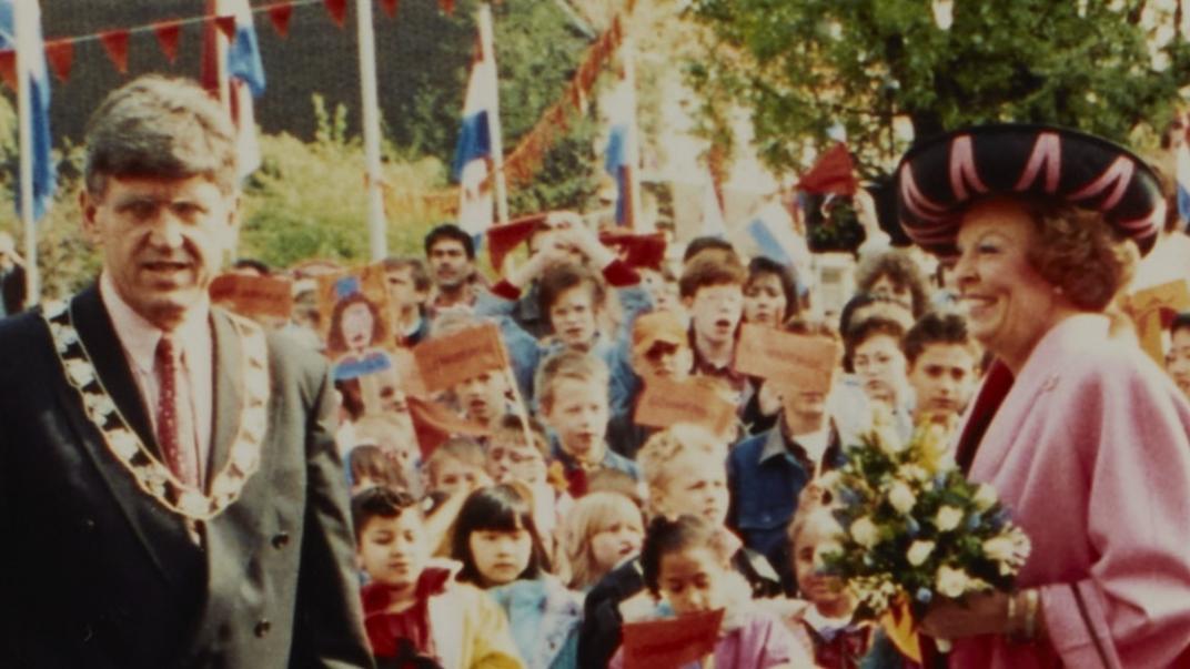 Koningin Beatrix langs een stoet mensen. Naast haar staat Burgemeester Peper